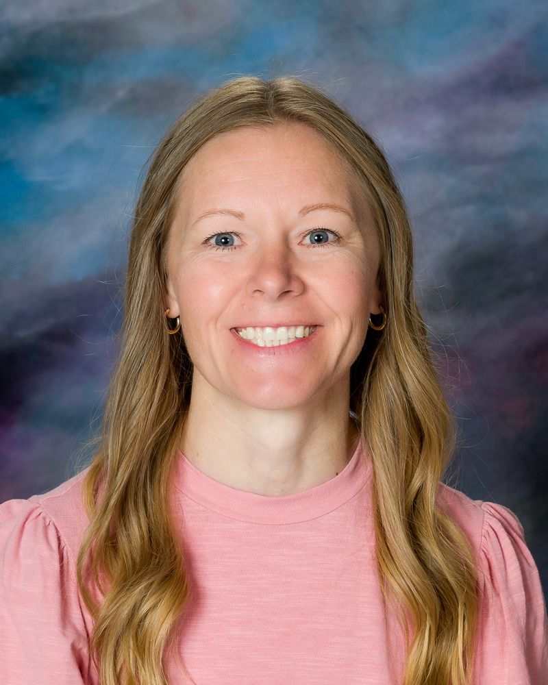 A woman in a pink shirt is smiling for the camera.