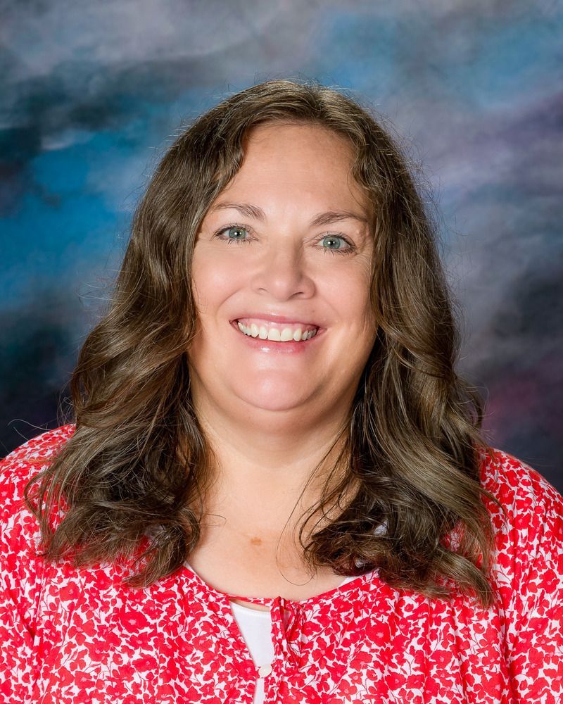 A woman in a red shirt is smiling for the camera.
