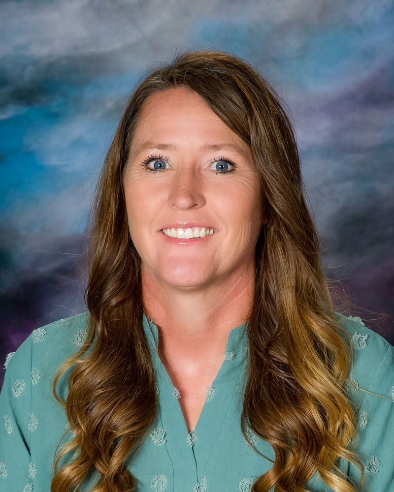 A woman in a green shirt is smiling for the camera.