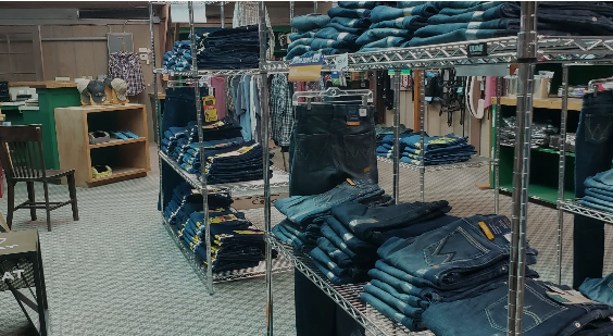 A store filled with lots of jeans and shirts on shelves.