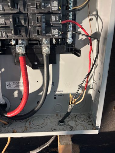 Open electrical panel with red, black, and gray wires connected to breakers and terminals.