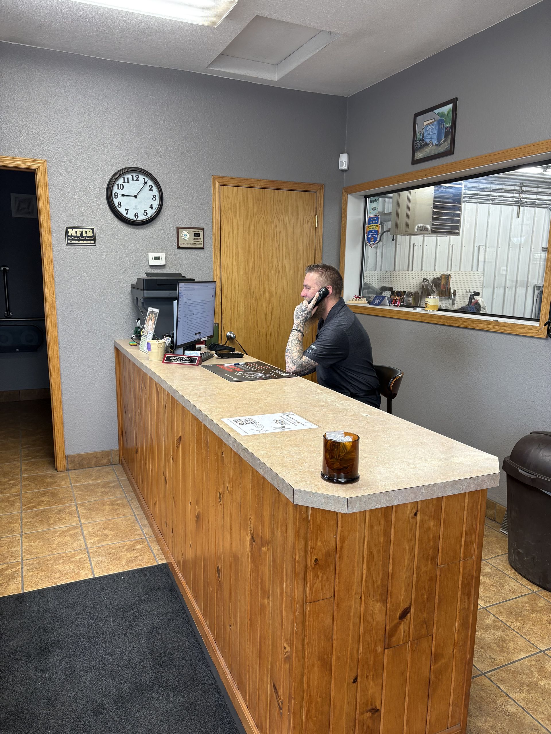Reception desk in a small office lobby, with a man seated on the phone behind the counter.