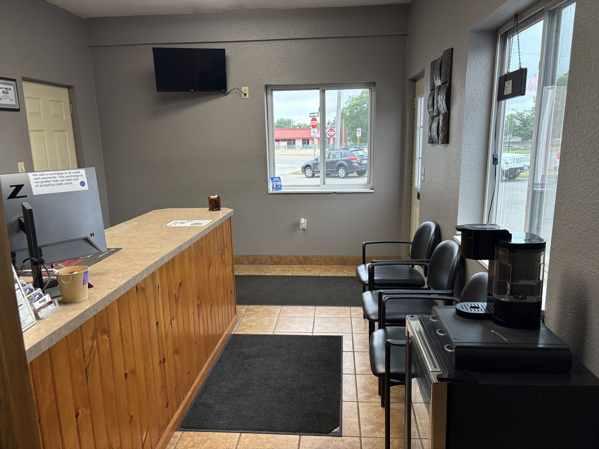 Small waiting room with counter, chairs, black rug, and windows facing outside.