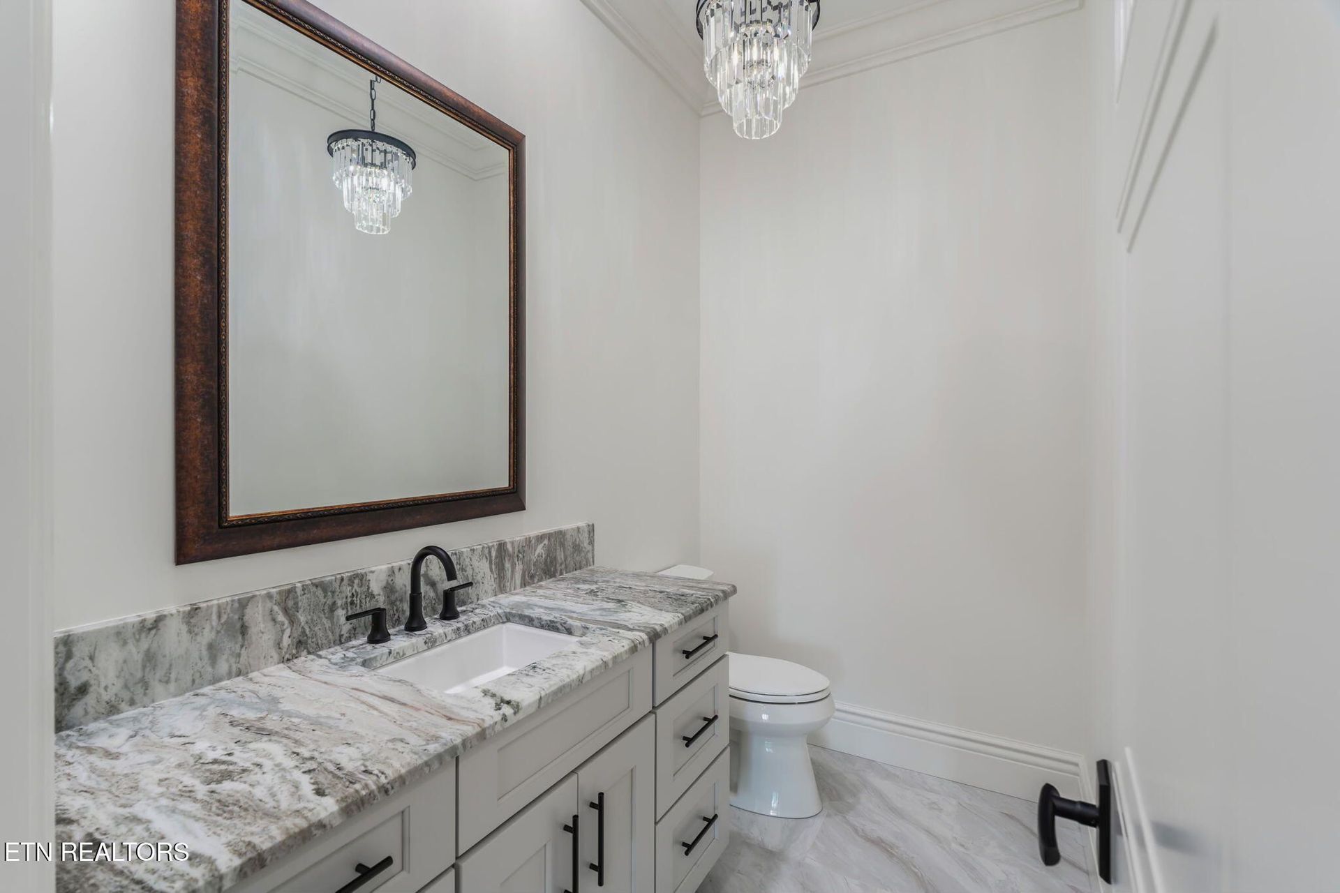 Modern bathroom with double vanity, large mirror, marble countertop, and white walls
