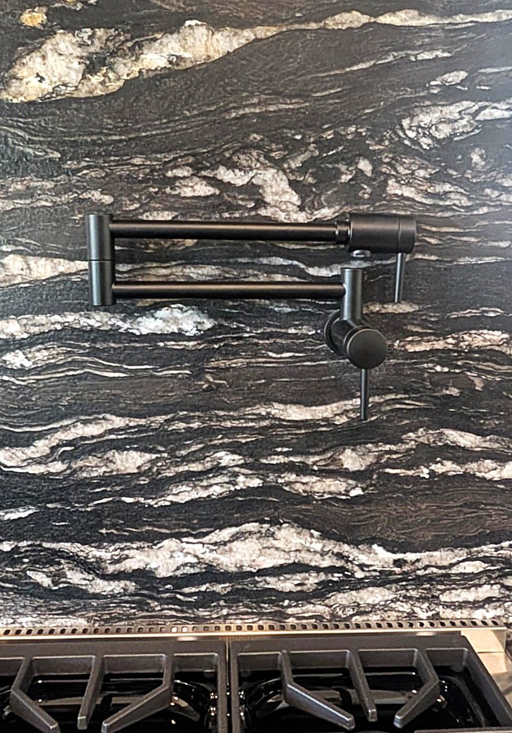 Black-and-white marble backsplash with a black faucet above a gas stovetop