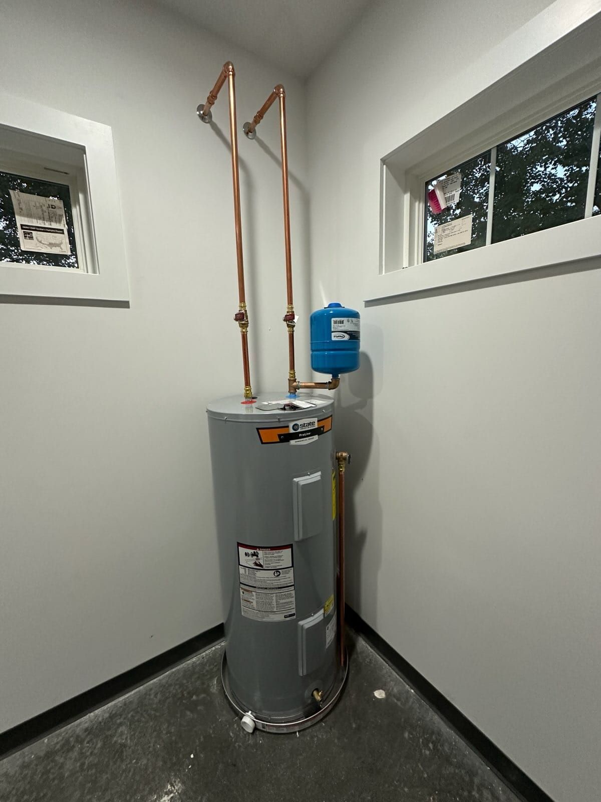 Water heater in a small utility closet with copper pipes and a blue expansion tank on top.