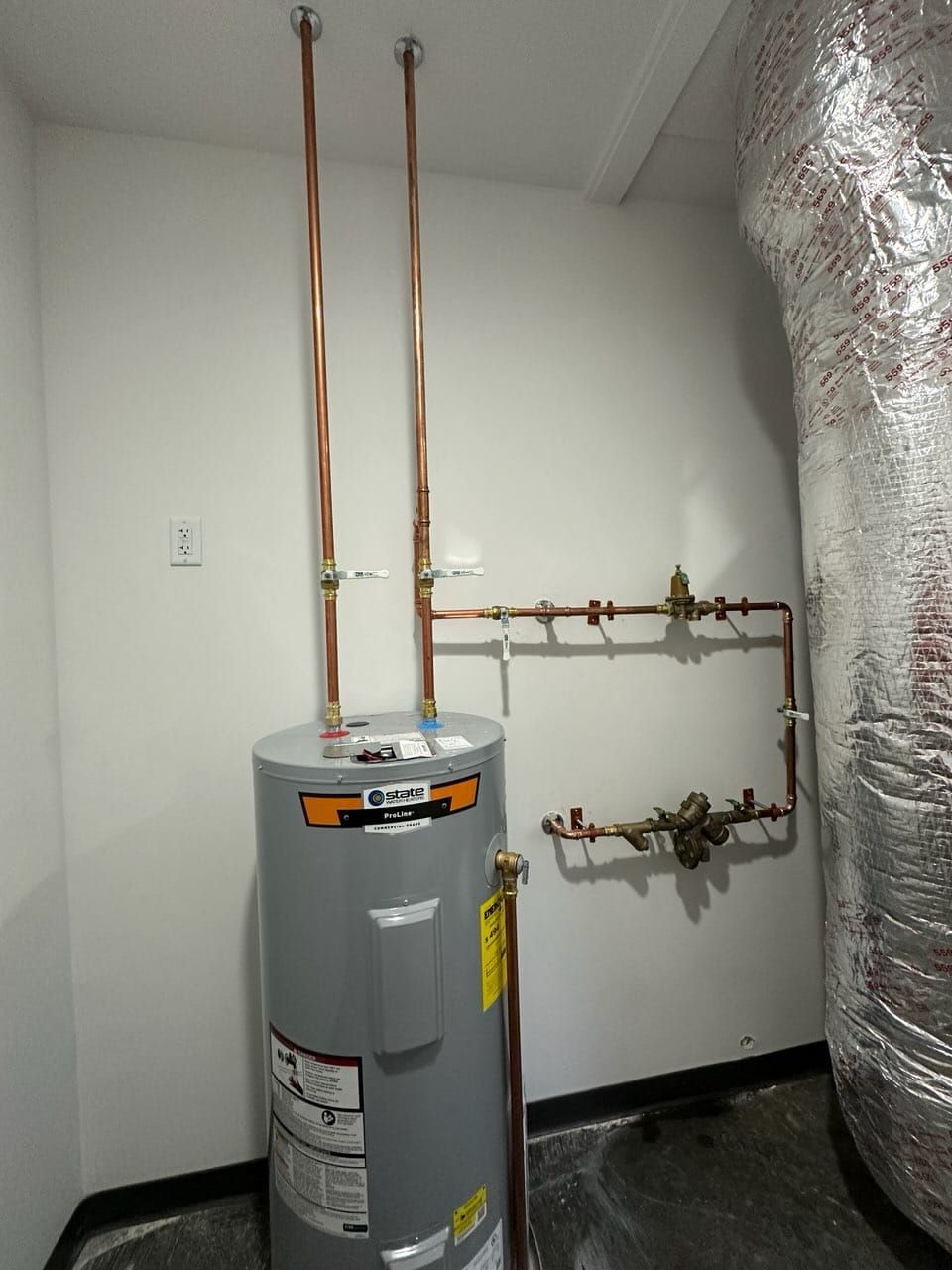 Water heater in a utility closet with copper pipes and insulated ducting.