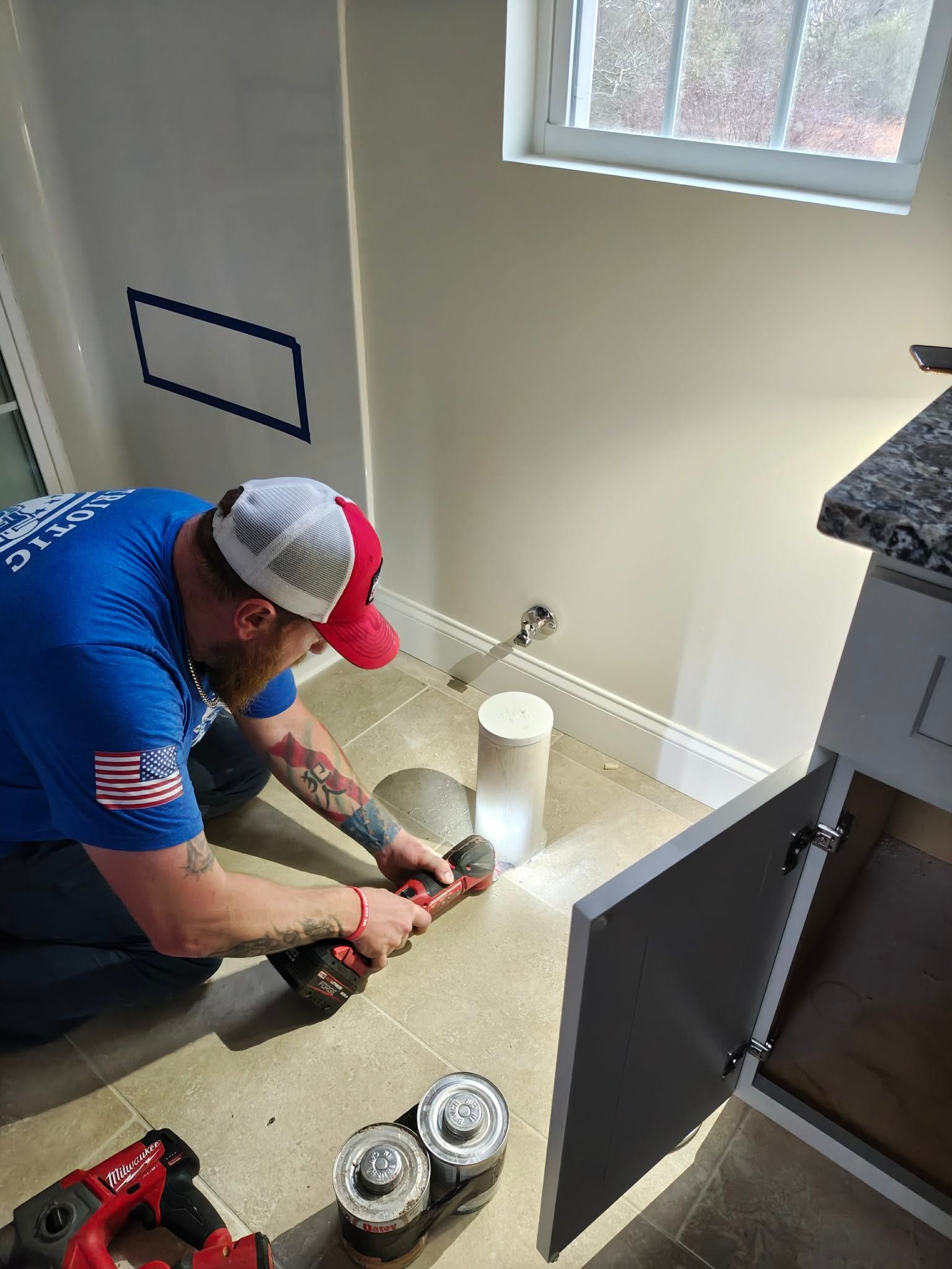 Worker using power tools to cut flooring in a kitchen during renovation