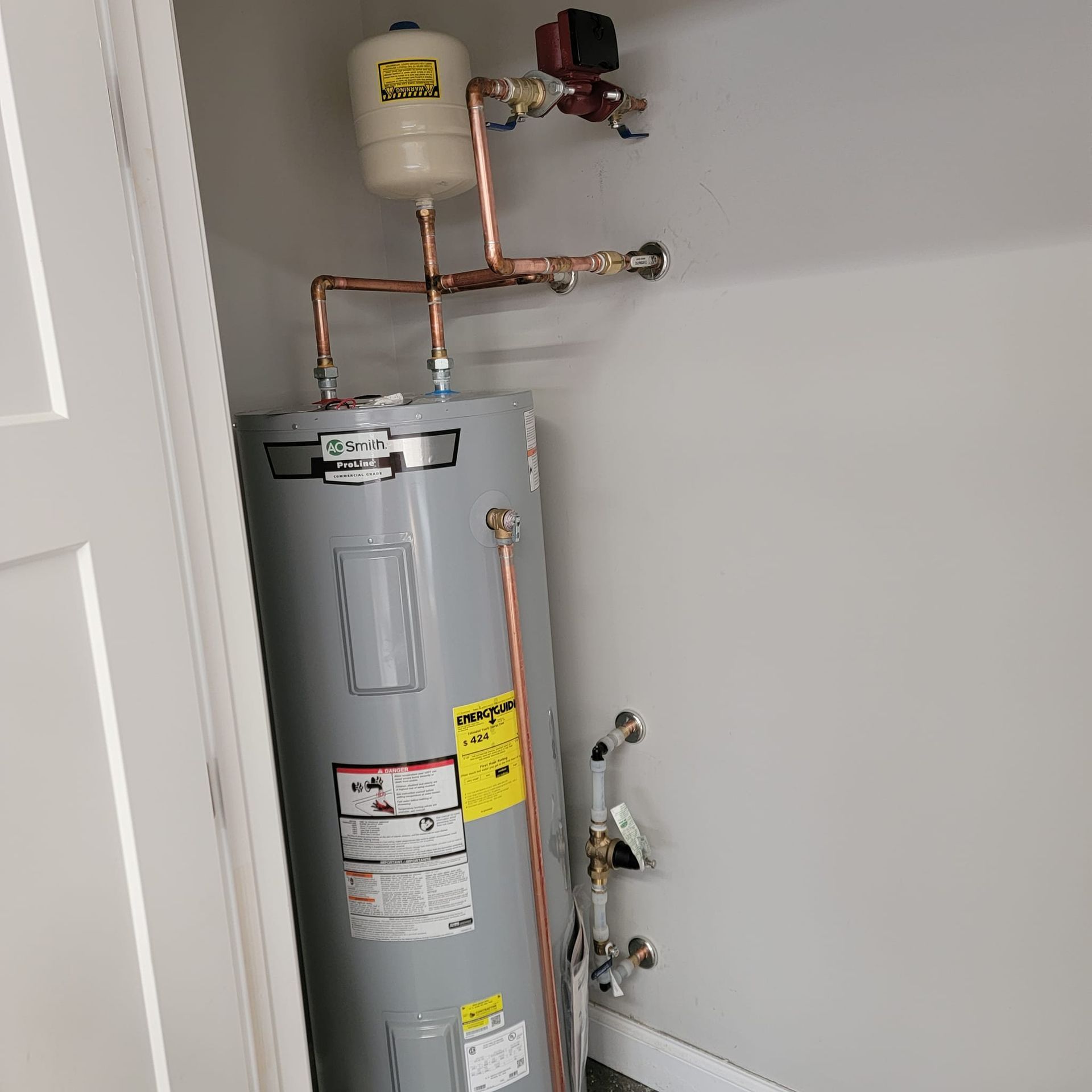 Water heater and copper plumbing in a utility closet, with a white expansion tank above.