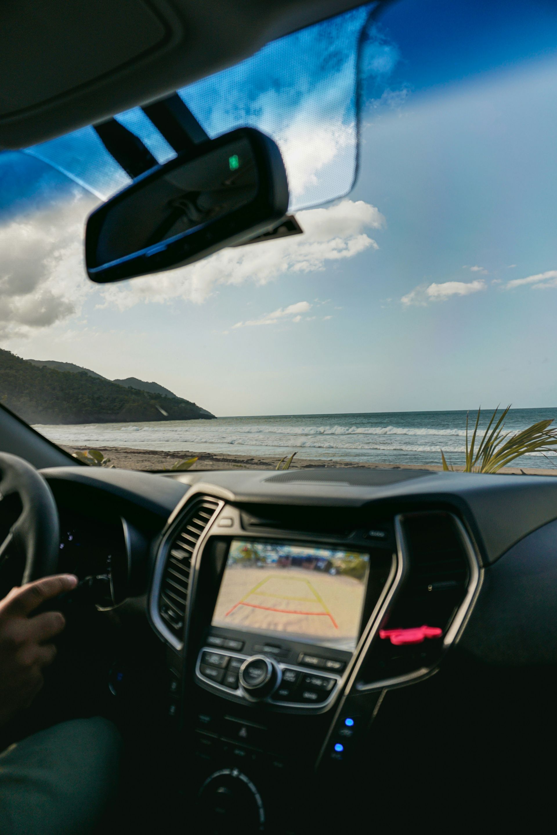 A person is driving a car on a beach near the ocean.
