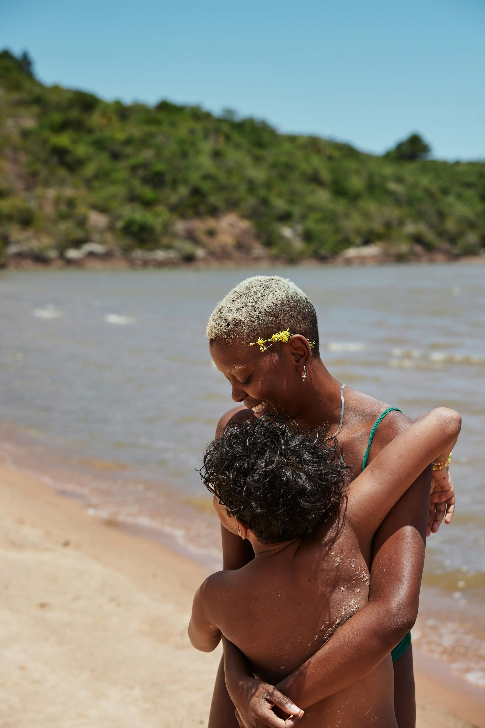 A woman is hugging a child on the beach.