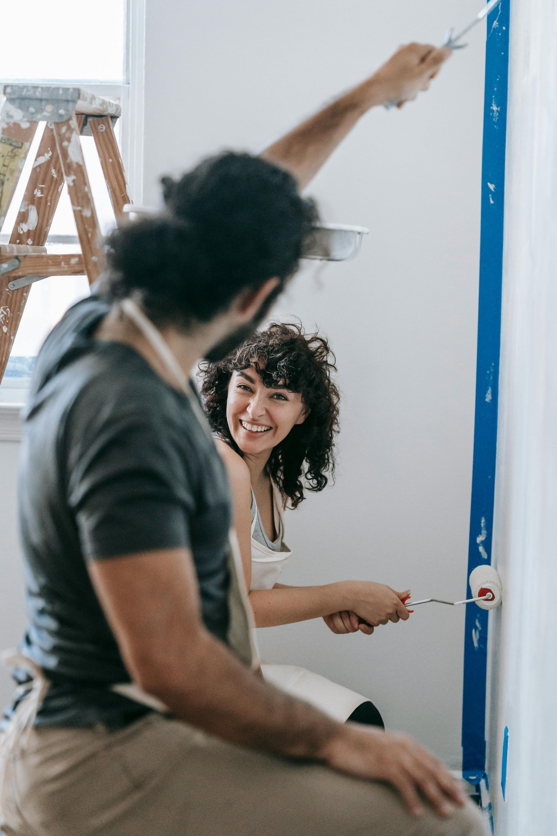 A man and a woman are painting a wall together.
