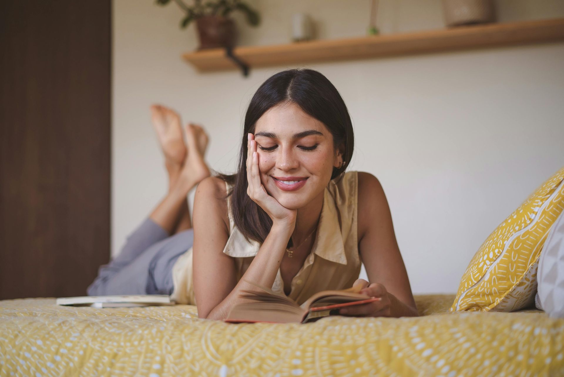 A woman is laying on a bed reading a book.