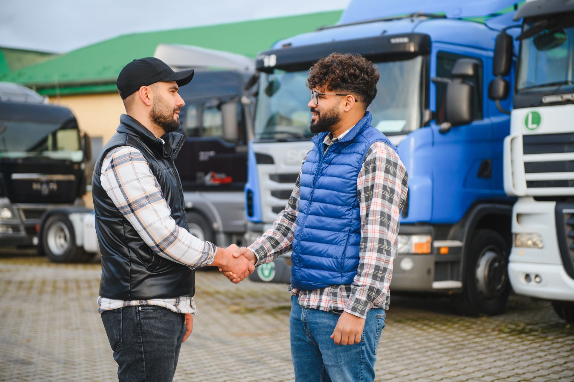 Truck drivers handshaking, completing a business agreement in a lot full of trucks. Truck drivers handshaking, completing a business agreement in a lot full of trucks.
