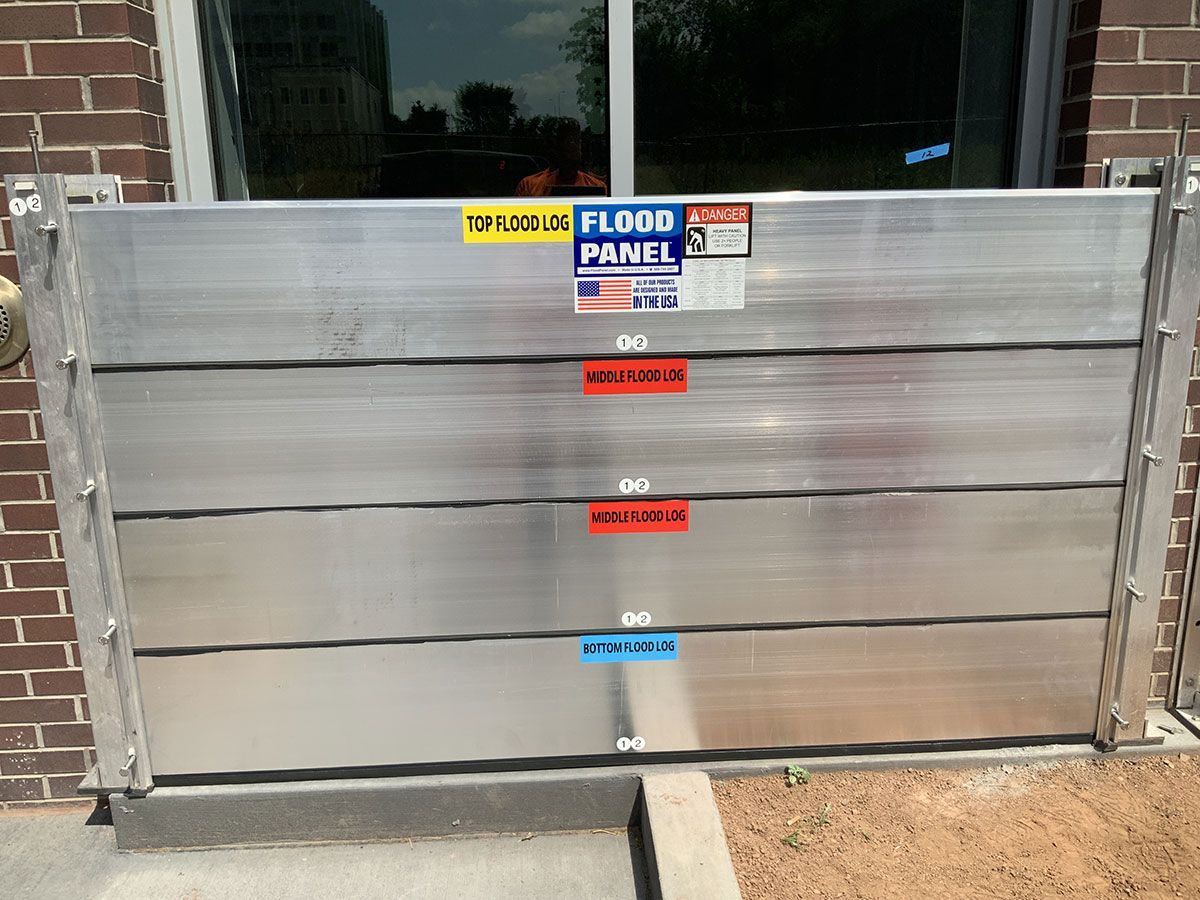 A flood panel is sitting in front of a brick building.