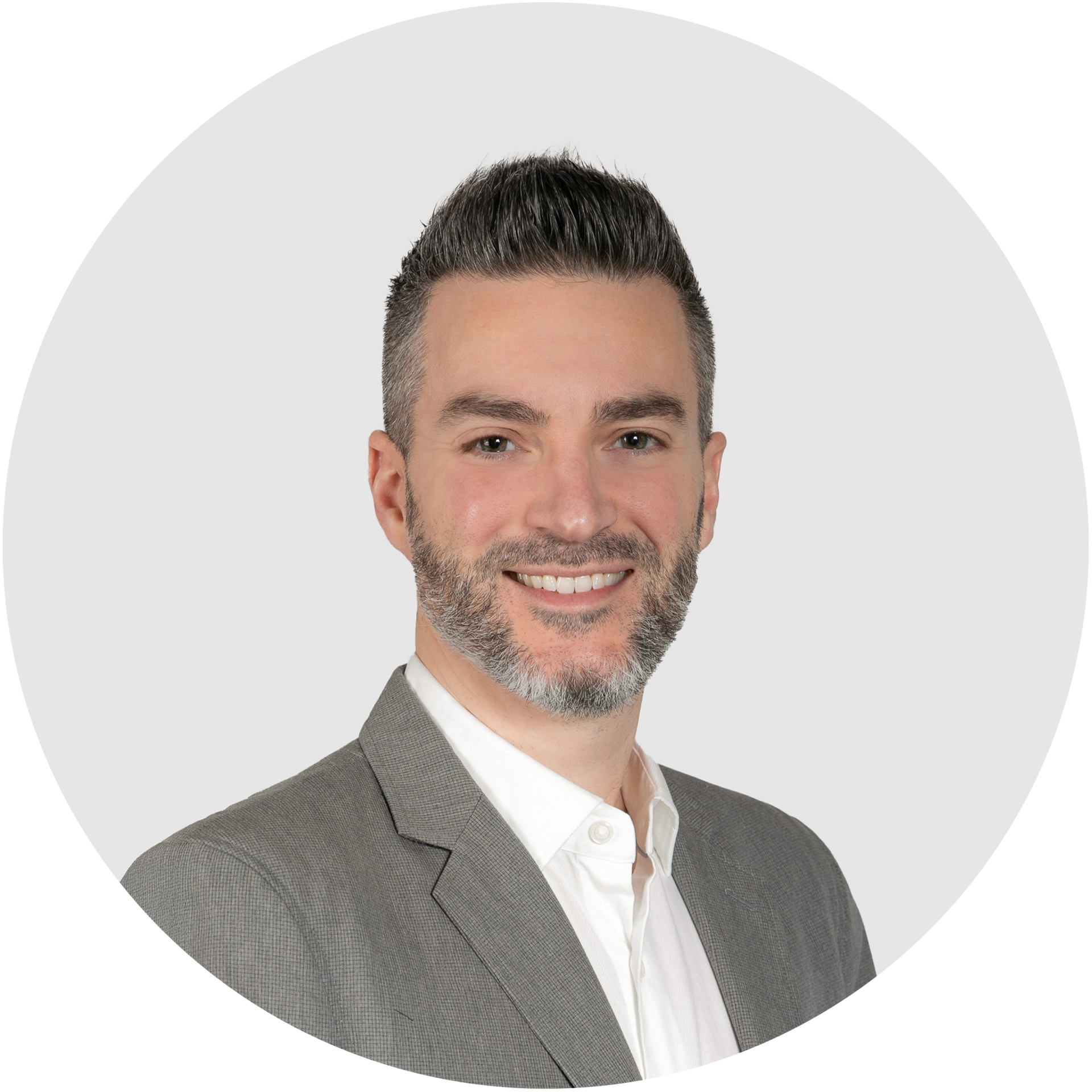A man with a beard is wearing a suit and smiling in a circle.