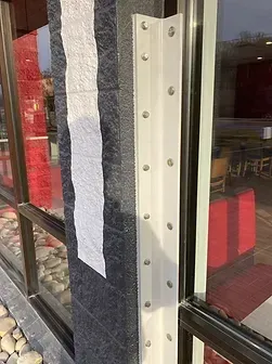 A close up of a window with a white corner guard on it.
