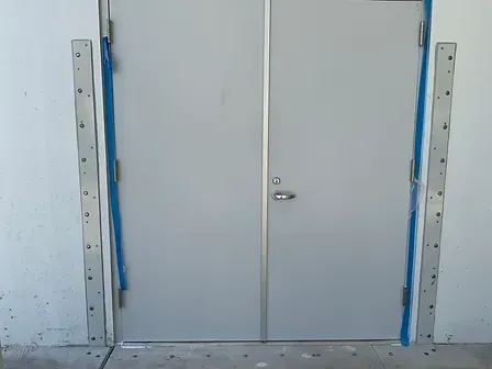 A white door with a stainless steel frame on a white wall.