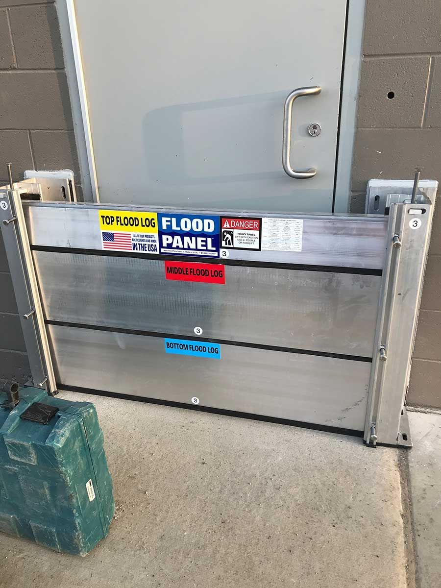 A flood panel is sitting on the sidewalk next to a door.