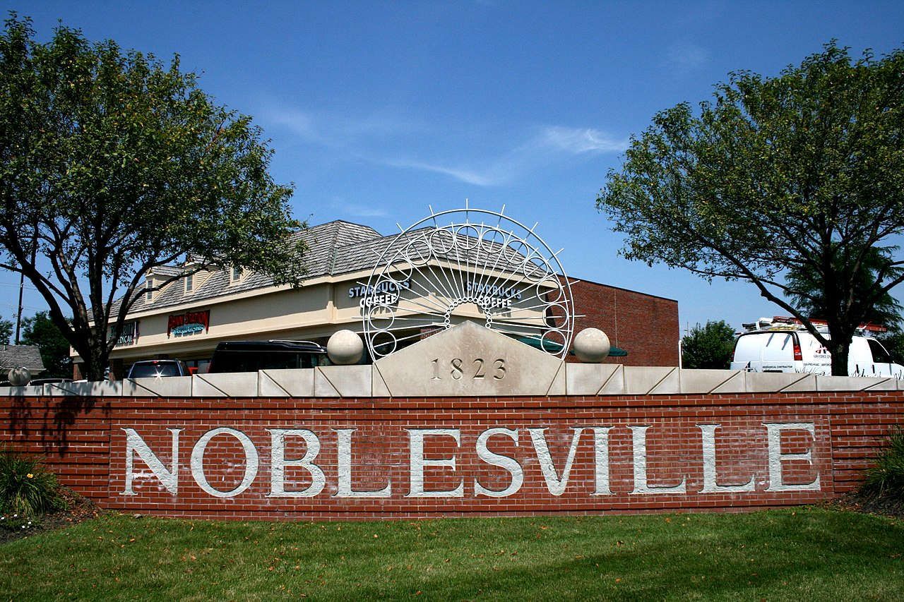 A sign for noblesville is painted on a brick wall