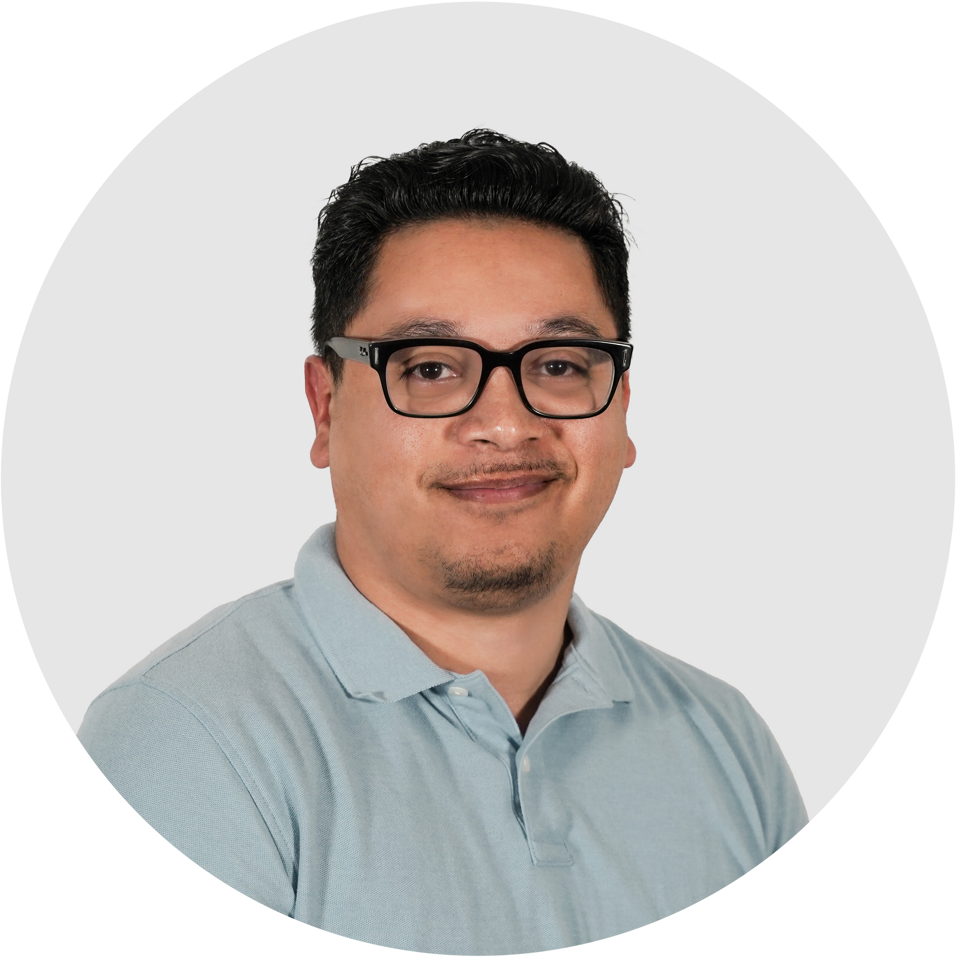 A man wearing a grey polo shirt is smiling for the camera