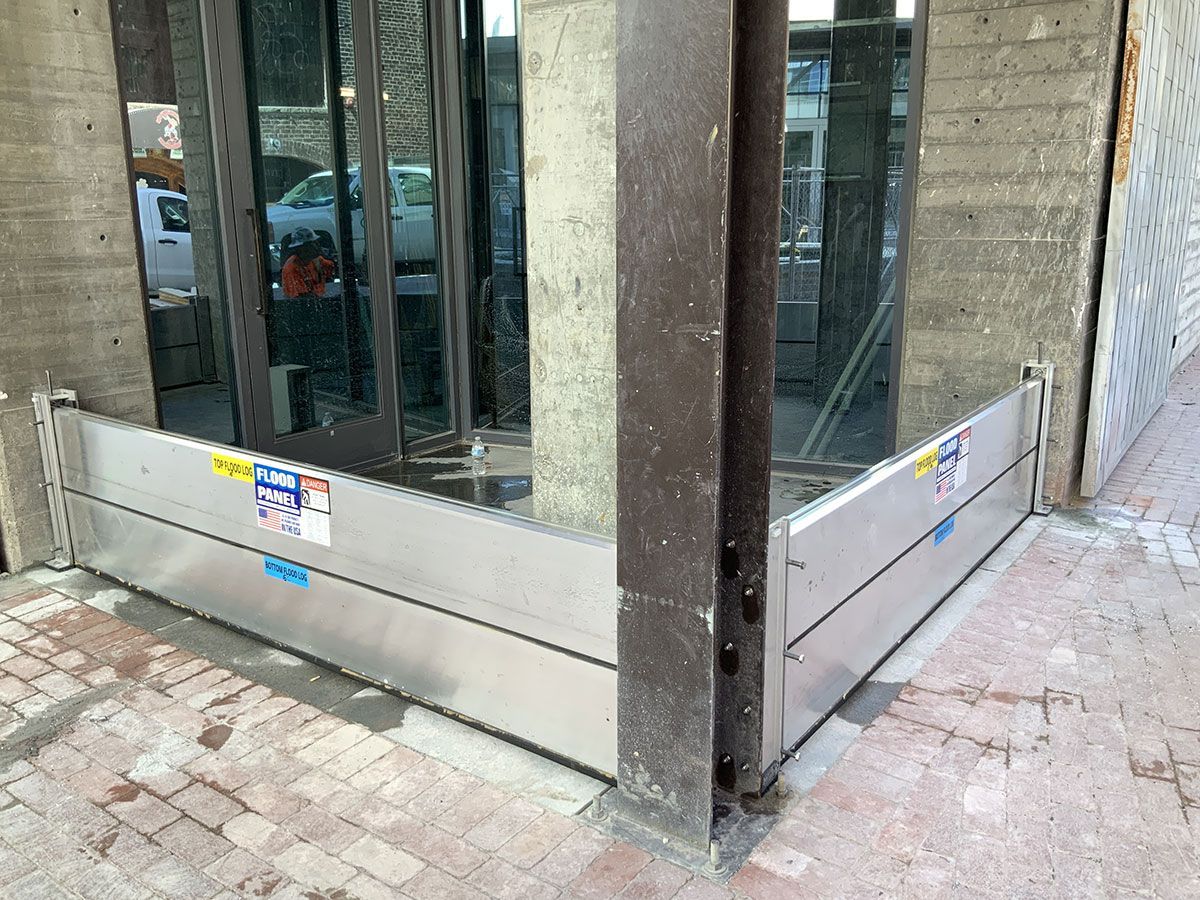 A metal barrier is sitting on the sidewalk in front of a building.