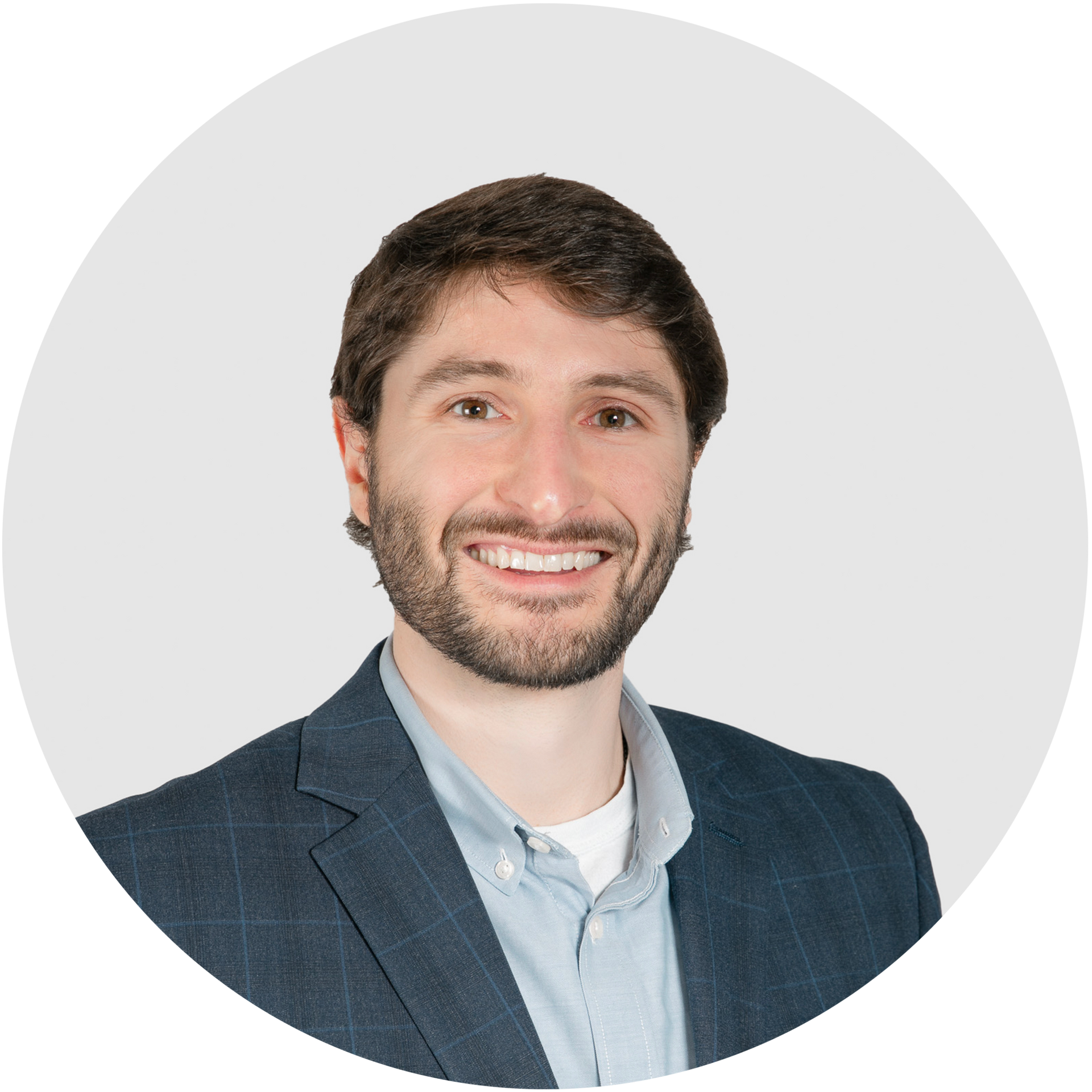 A man with a beard is wearing a suit and smiling in a circle.