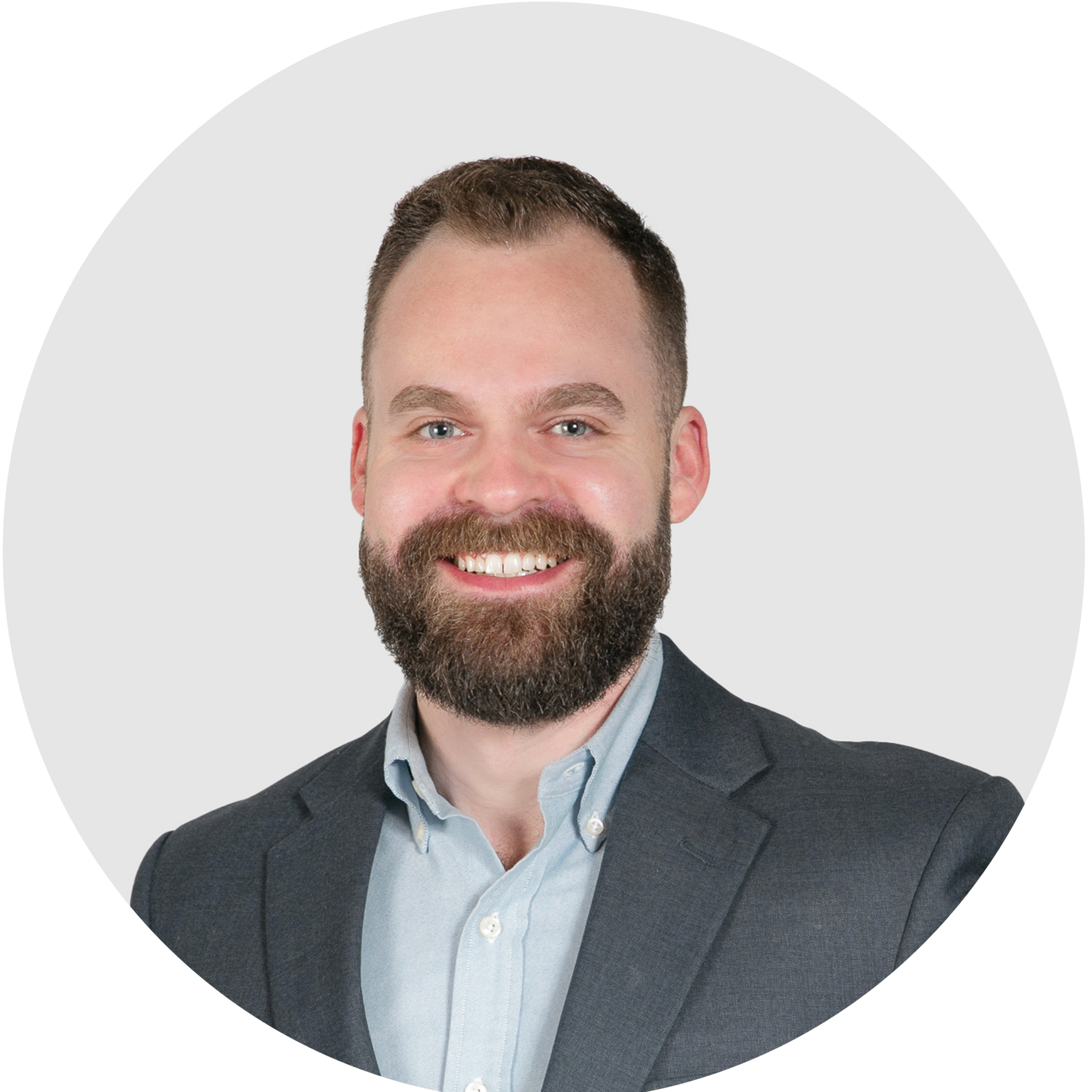 A man with a beard is wearing a suit and smiling.