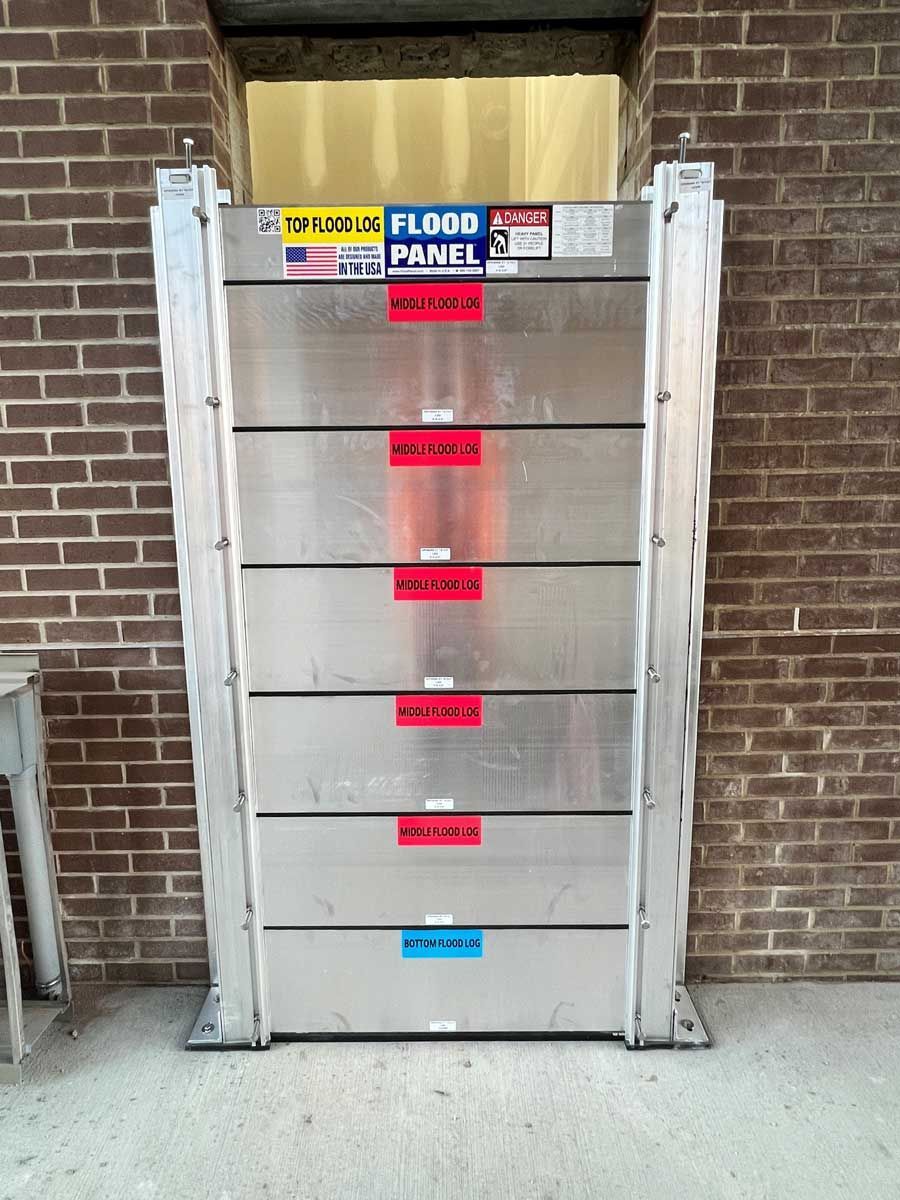 A stainless steel flood panel is sitting in front of a brick wall.