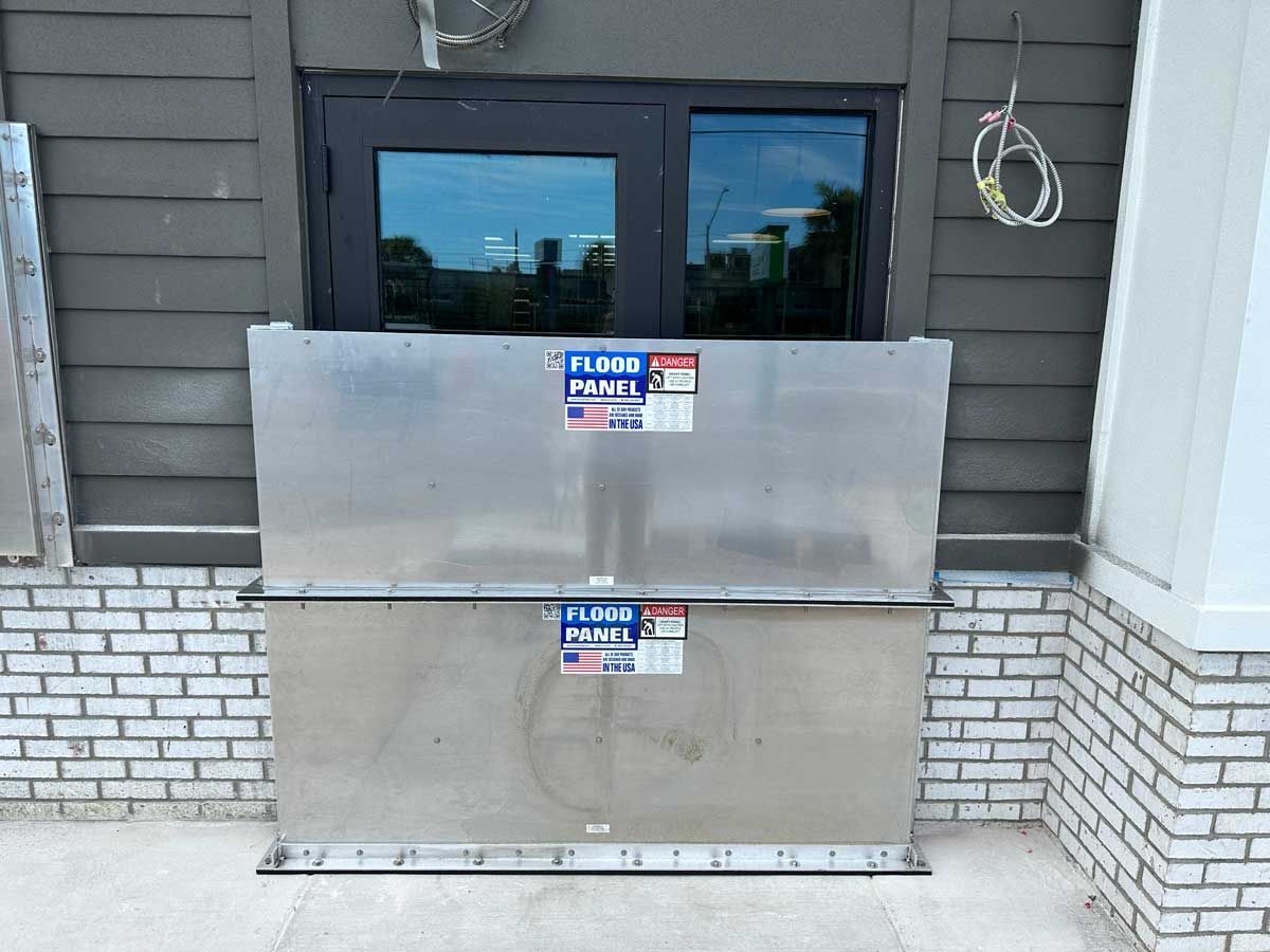 A stainless steel box is sitting on the side of a building next to a window.
