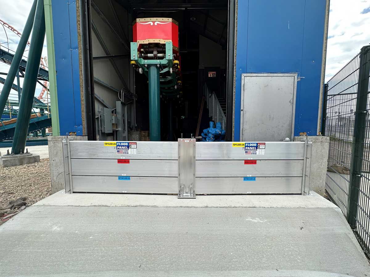 A roller coaster is parked in the back of a building next to a fence.