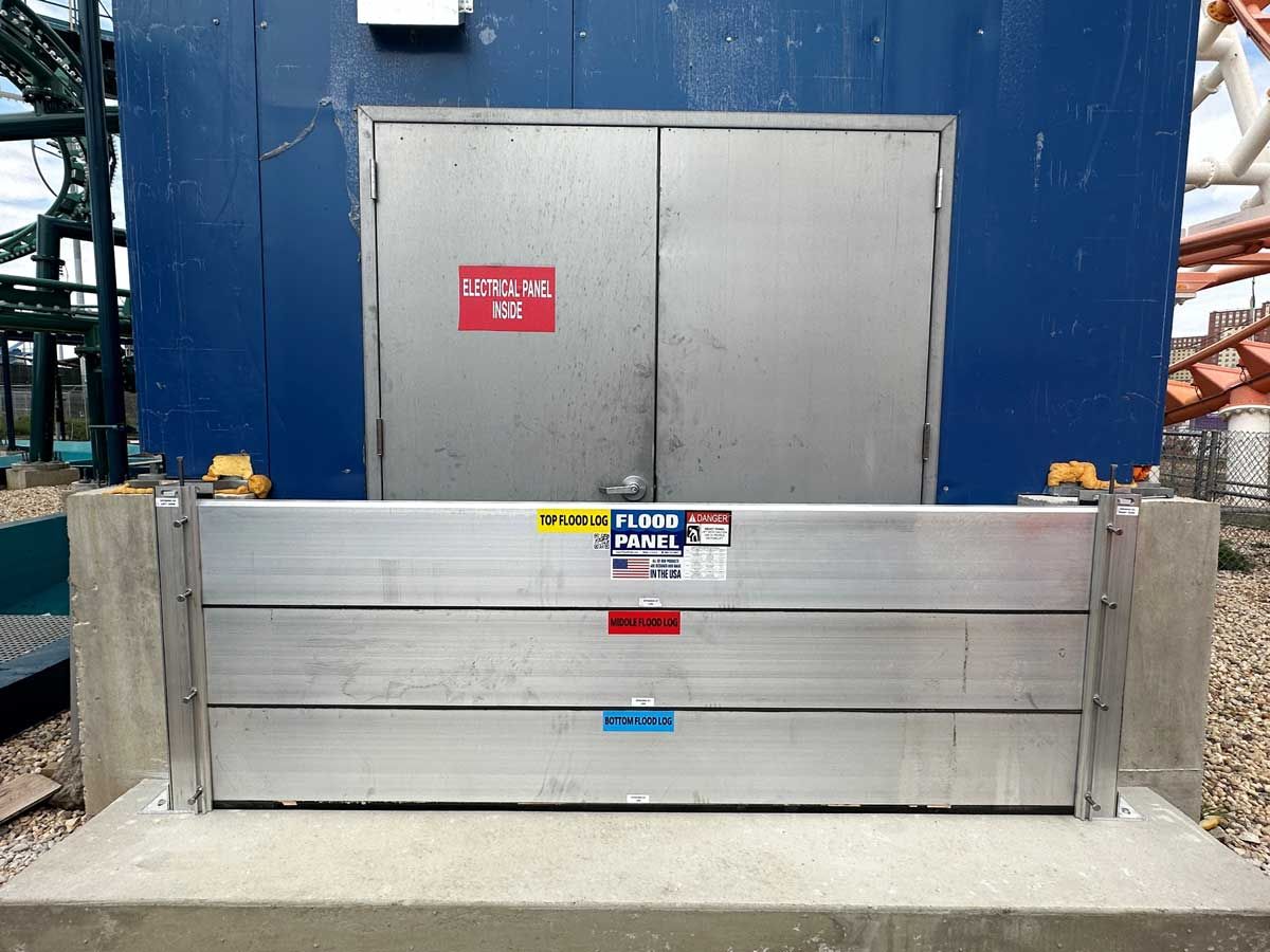 A flood barrier is sitting in front of a blue building.