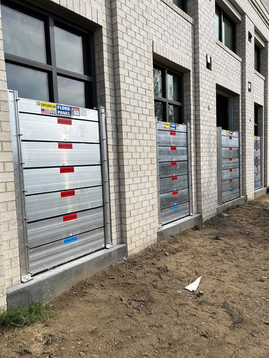 A row of flood barriers on the side of a brick building.