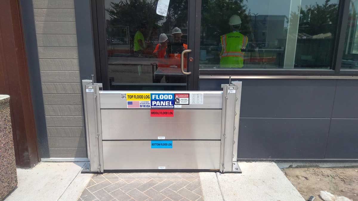 A flood barrier is sitting outside of a building next to a door.