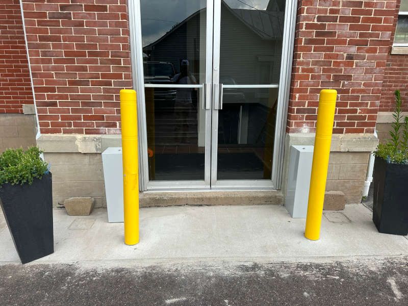 A brick building with two yellow poles in front of it.
