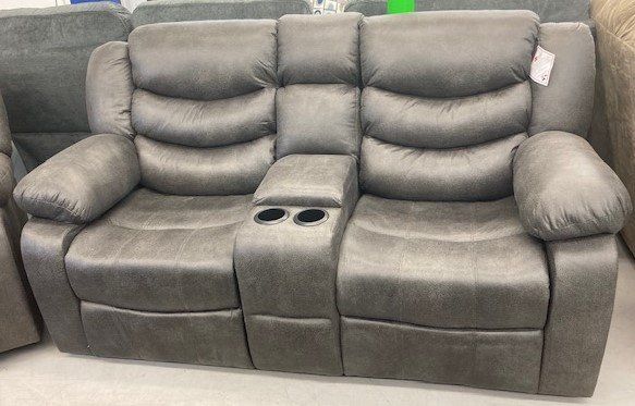 A grey recliner couch with two cup holders on the arm rests is sitting in a store.