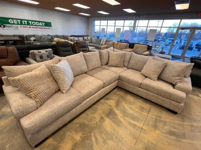 A large sectional couch in a store with a sign that says get it today