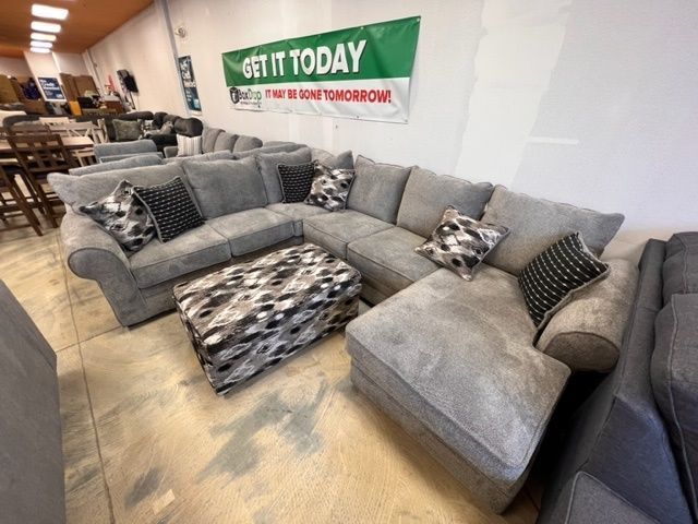 A large sectional couch is sitting in a store with a sign that says get it today.