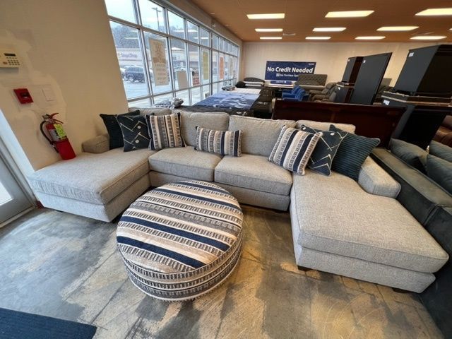 A living room with a sectional couch and an ottoman