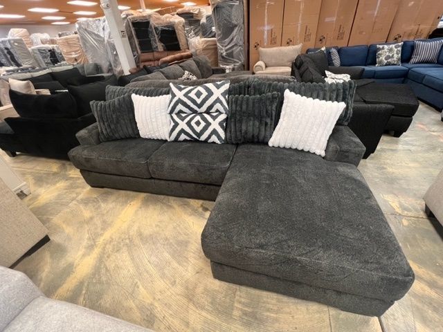 A gray sectional couch with white pillows in a store