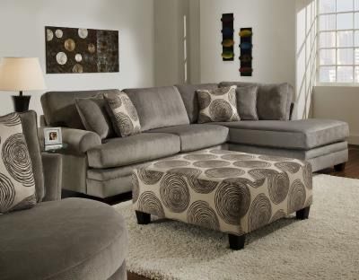 A living room with a sectional couch , chair , ottoman and rug.