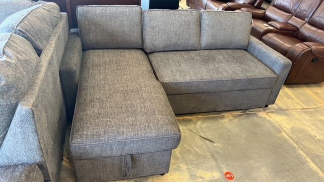 A sectional couch is sitting on a tiled floor in a store.
