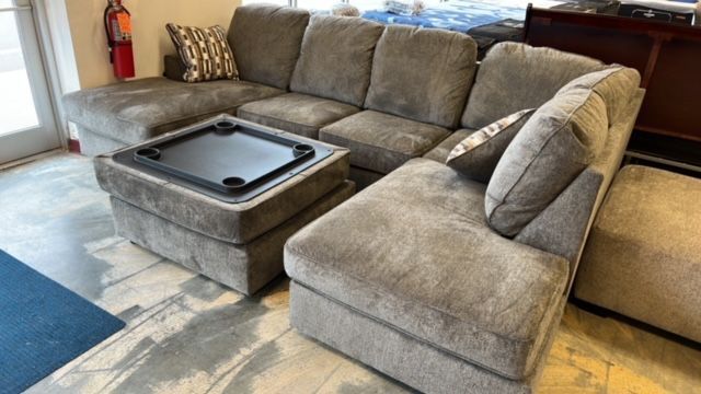 A sectional couch with a coffee table on top of it in a living room.