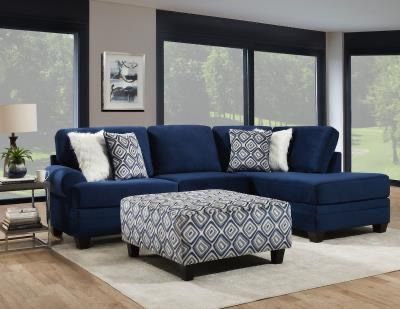 A living room with a blue sectional couch and an ottoman.