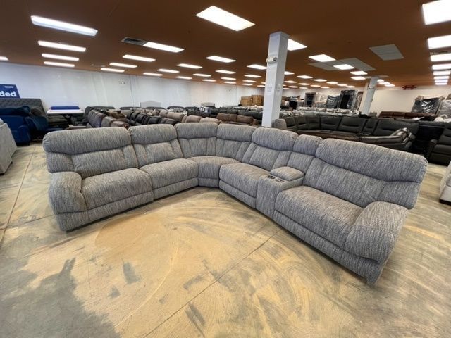A large sectional couch is sitting in a large room.