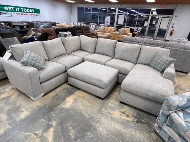 A sectional couch and ottoman in a store with a sign that says get it today