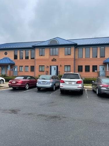 Brick apartment building with blue roof and parked cars in front on a rainy day
