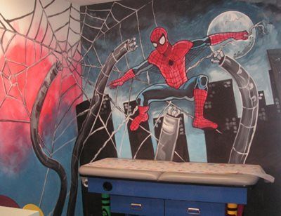 Spider-Man mural on a bedroom wall with web patterns and a moonlit city scene above a blue dresser