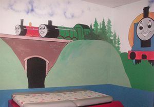 Children’s room mural of smiling Thomas the Tank Engine trains on green hills and a bridge