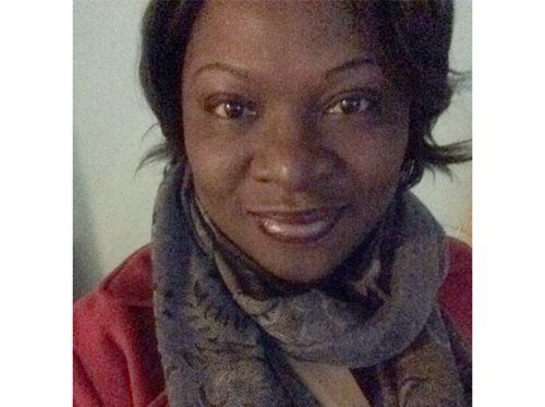 Close-up portrait of a smiling person wearing a red top and gray scarf against a plain background
